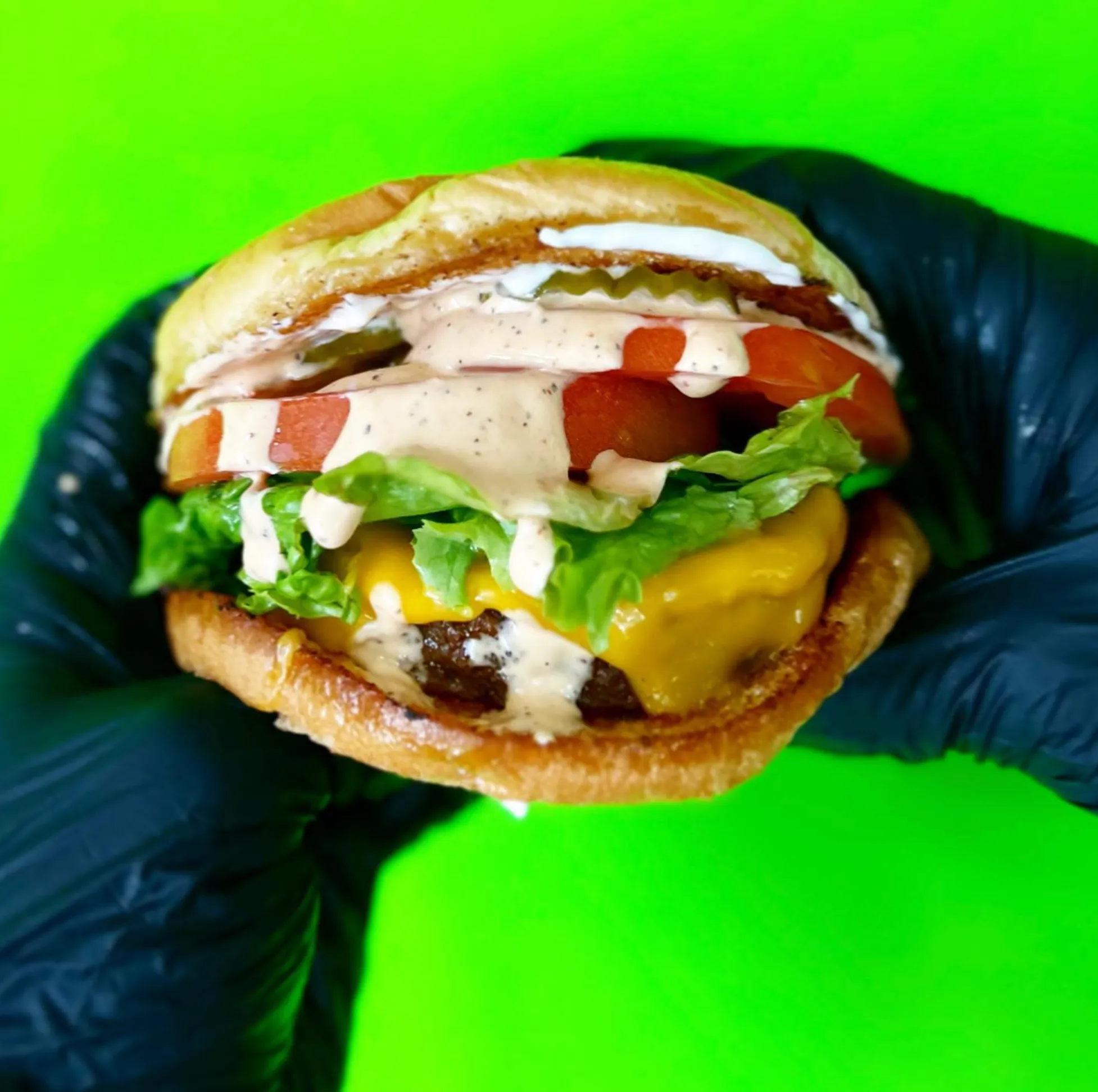 A loaded vegan sandwich held up against a lime green background